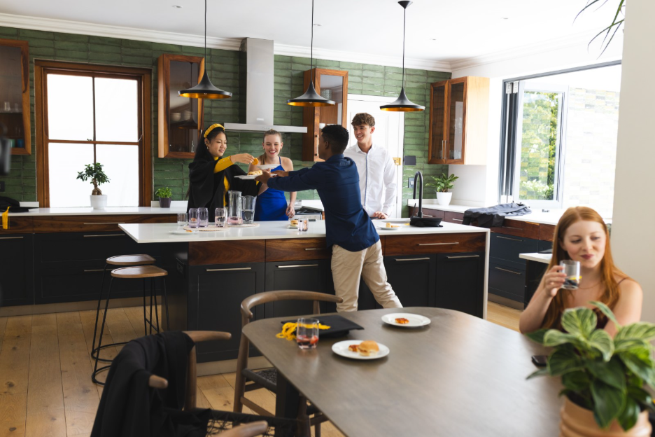 amily and friends gathering in a modern kitchen with dark cabinetry, wood accents, pendant lighting, and a large island for entertaining.